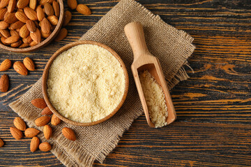 Bowl and scoop with almond flour on wooden background