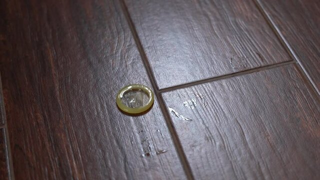 Close-up of twisted condom falling to the floor
