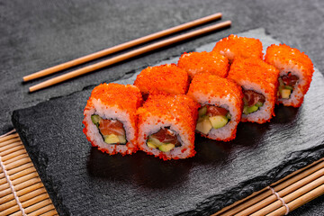 Golden dragon sushi roll with crab, salmon, cucumber, sesame seeds and cream cheese over black backgraund. Top view