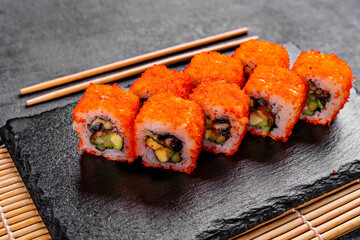 Golden dragon sushi roll with crab, salmon, cucumber, sesame seeds and cream cheese over black backgraund. Top view