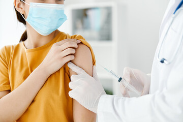 side view of a doctor injecting a vaccine into the shoulder of a patient wearing a medical mask