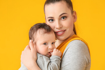 Young mother with little baby in sling on color background