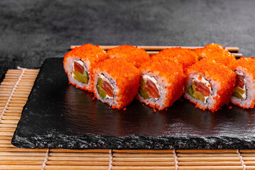 Golden dragon sushi roll with crab, salmon, cucumber, sesame seeds and cream cheese over black backgraund. Top view