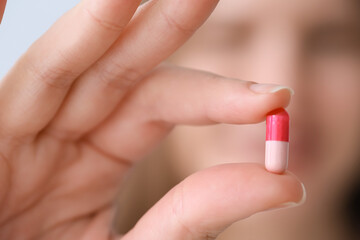 Beautiful young woman with pill, closeup