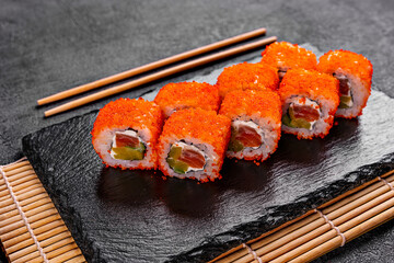 Golden dragon sushi roll with crab, salmon, cucumber, sesame seeds and cream cheese over black backgraund. Top view