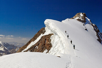 Bunch of mountaineers climbs to the top of snow capped mountain, Fann, Pamir Alay,