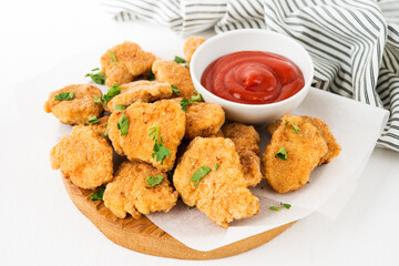 Homemade chicken nuggets with ketchup on a wooden board