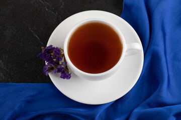 Dried purple flowers with a cup of hot tea on a black background