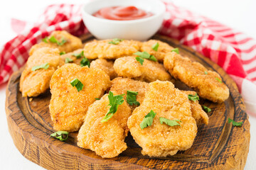 Homemade chicken nuggets with ketchup on a wooden board
