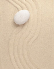 Fototapeta na wymiar One white stone on the sand top view vertical photo concept zen