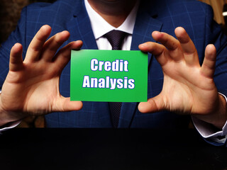 Blank green business card in a hand with phrase Credit Analysis . Horizontal shot.