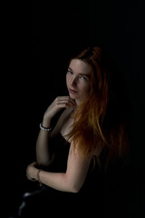 Fototapeta premium Face Close up of Ginger hair young white woman touching her chin with black background