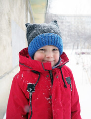 Portrait of a smiling boy eight years old in winter outdoor during a snowfall.