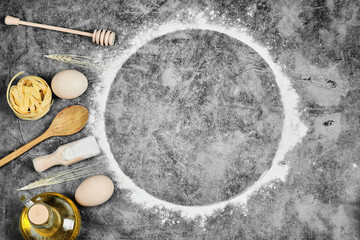 Eggs, flour, oil, raw pasta, and wooden spoons on the marble background
