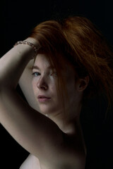 Ginger hair young white model holding her hair with black background