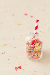 Colorful heart and star sprinkling in a little bottle with striped red and white straw