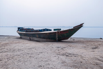 Wooden fishing boat on the beach with foggy sky.