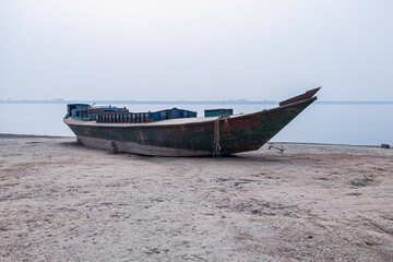 Obraz premium Wooden fishing boat on the beach with foggy sky.