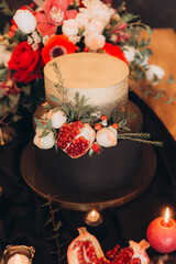 Festive table with black decor, candles, cake and flowers, marsal and garnet, gold cutlery