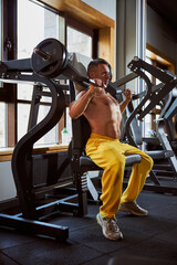 Fototapeta premium Focused athletic man working out on gym machine