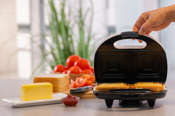 Opening the lid of a sandwich making machine