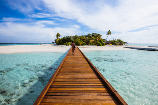Woman walking on jetty to island, Maldives