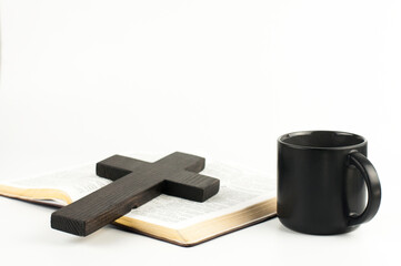 The open book is the holy bible. Scripture. Wooden cross of Jesus. Chorna cup with coffee