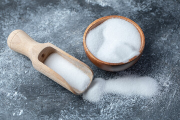 Salt in a wooden spoon on a marble background