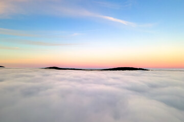 Aerial view of vibrant yellow sunrise over white dense clouds an
