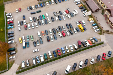 Aerial view of many colorful cars parked on public parking lot.