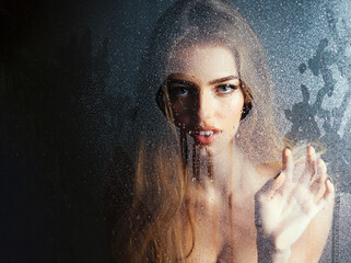 Sexy woman. Window with water drops before girl with makeup. Shower and hygiene spa treatment. Rain drops on window glass in heart shape. Fashion beauty.