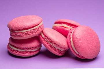 Colorful sweet macarons or macaroons, flavored cookies on purple background.