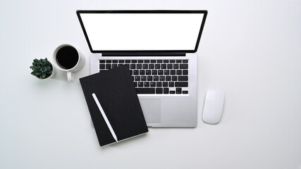 Overhead shot of modern minimal workplace with computer laptop, notebook, coffee cup and plant on white background.