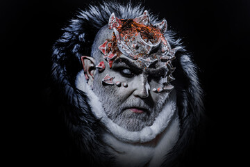 Dark arts concept. Devil man with white beard dressed like monster. Evil on black background, close...