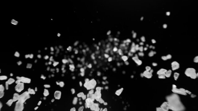 Super slow motion of falling whole grained salt pieces on black background. Filmed on high speed camera, 1000 fps