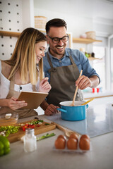 Happy young couple enjoys and having fun preparing healthy meal together at home kitchen.