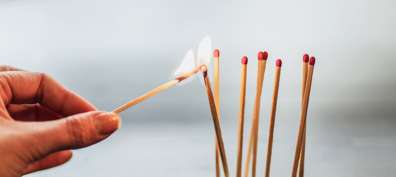 hand lighting a match in a group of matches. white and grey blurred background