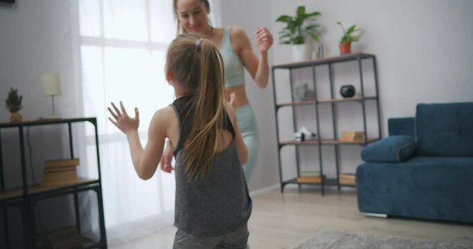 cheerful mother and daughter are playing blind man's buff in living room of apartment after sport training