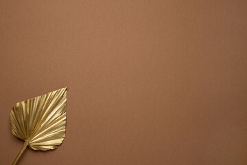Gold tropical leaf on brown background with copy space , trend decoration