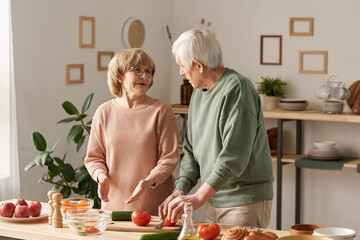 Senior couple discussing the menu for dinner while cooking together in the kitchen