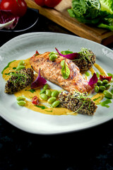 Grilled Salmon steak with quinoa and green beans, yellow sauce, served on a white plate. Restaurant food. Seafood dish