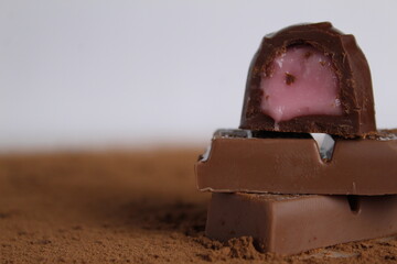 Chocolate candy lies on chocolate and cocoa on a white background with a place for text and copyspace