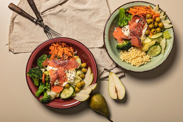 Two bowls of poke with salmon, broccoli, carrots, pears and ptitim pasta. Seafood and vegetables. Healthy diet. Top view