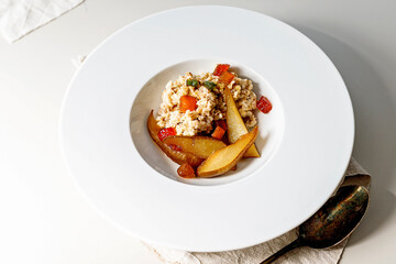 Oatmeal with fruits on a white plate. Sweet pear and candied fruits. Delicious and healthy breakfast. Ideas and recipes for home meals.