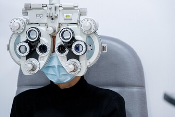 Young patient eye examination at optometrist using phoropter