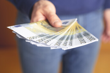 A man holds cash euros in his hand. Money, business, profit and livelihood concept. Selective focus