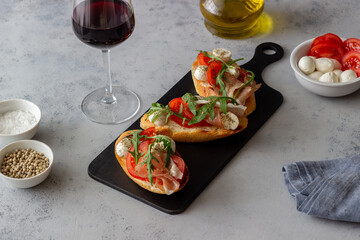 Bruschetta with ham, mozzarella, tomatoes and arugula. Wine appetizer. Snack.