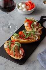 Bruschetta with ham, mozzarella, tomatoes and arugula. Wine appetizer. Snack.