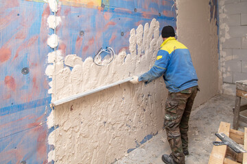 A worker plasters the walls in the room.