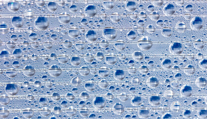 Water drops on blue glass as an abstract background.